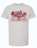 Silver gray tshirt with graphic design of a book laid open with the dallas skyline coming out of it and text underneath reading "Support your local library" in maroon ink.