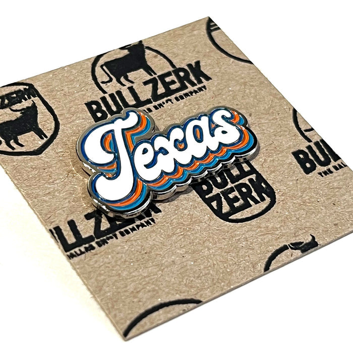 Close-up view of the Texas Script Enamel Pin on textured kraft paper, highlighting the colorful lettering, making it a great Texas themed gift, Texas Made Gifts, and a lovely choice among souvenirs from Texas for fans of Dallas souvenirs and Texan gifts.