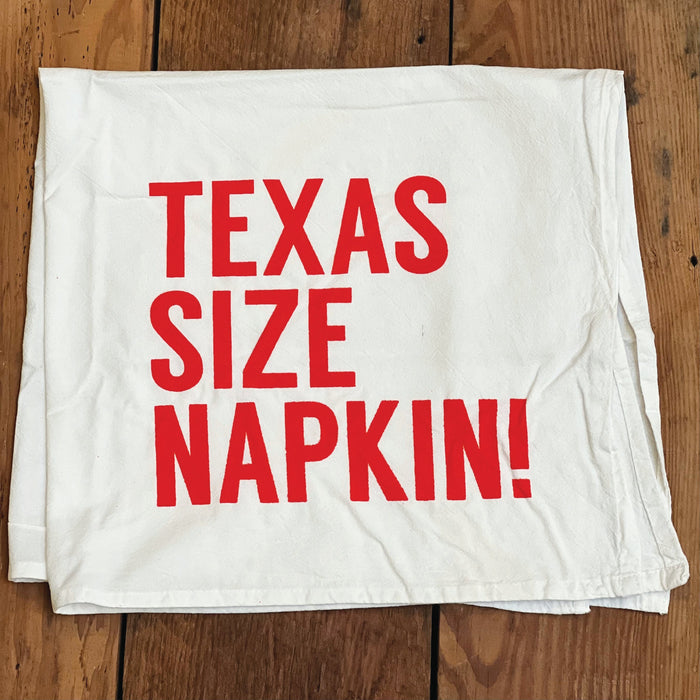 Texas Size Napkin Tea Towel featuring bold red lettering on a white background, perfect for a Texas themed gift, Texas Made Gifts, and great souvenirs from Texas. This tea towel makes an ideal addition to any kitchen and a wonderful Dallas souvenir for those who love Texan gifts.