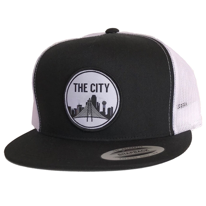 The City Patched Flat Bill Hat featuring a black and white design, perfect for anyone looking for a cool Texas themed gift. This snapback hat showcases a stylish city skyline patch, making it a great Texas Made Gift, ideal for souvenirs from Texas, especially for Dallas enthusiasts who love unique Texan gifts.