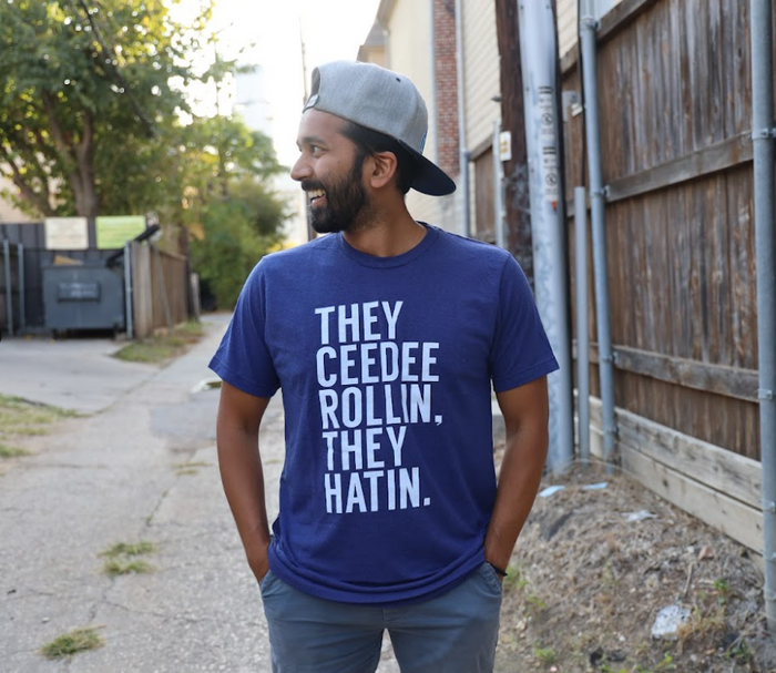 Man wearing a Bullzerk Ceedee Rollin tshirt, standing on a street.