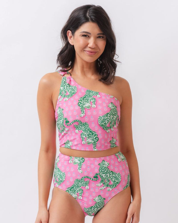 Photo of a woman wearing a bold pink and green tiger print one shoulder crop swim top with matching high waist swim bottoms