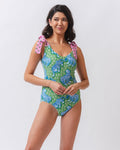 Photo of a woman wearing a bold green and pink tiger print shoulder tie swim one piece