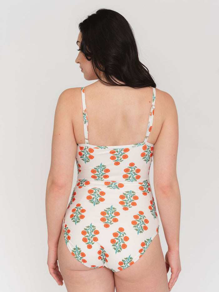 Back view of woman wearing a patterned swimsuit against a white background