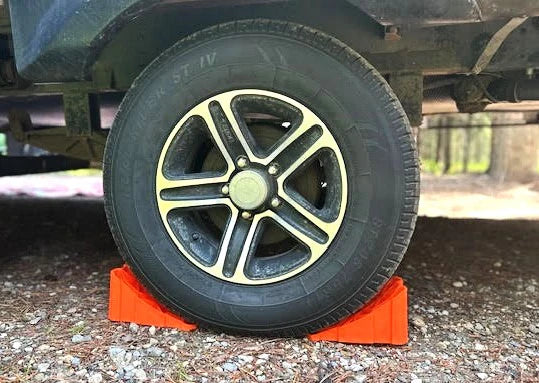 Orange Tri-Lynx Lil' Chock 00017 Securing Trailer Wheel on Gravel - In-Use Lifestyle Shot | United RV Parts