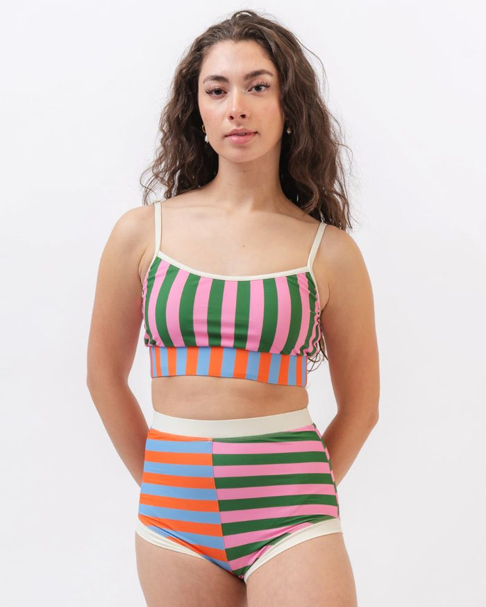 Photo of a woman wearing a multi-colored striped swim bralette and a multi-colored striped retro swim short bottom