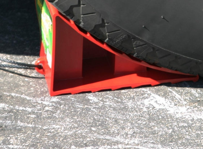 Red Valterra Wheel Chock Secured Under RV Trailer Tire on Pavement - In-Use View | United RV Parts