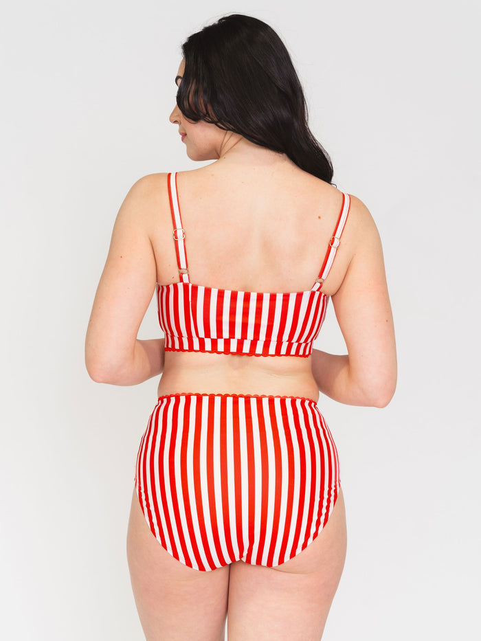 Back view of a woman wearing a red and white striped bikini set on a white background