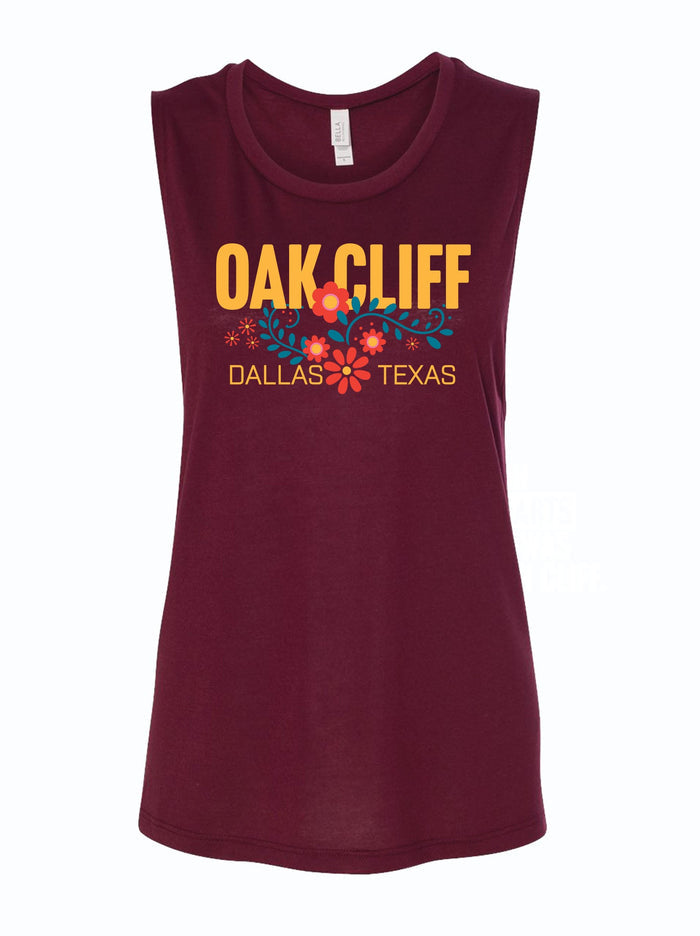 Women's Oak Cliff Floral Muscle Tank featuring a vibrant design with 'Oak Cliff, Dallas Texas' text. Perfect for anyone seeking Texas themed gifts, this tank top makes a great souvenir from Texas and a stylish addition to your Texan gifts collection.