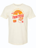 Cream tshirt with graphic design of a sunset over the Dallas skyline and text reading "You wish you were from Texas" above a folding chair and cooler with beer.